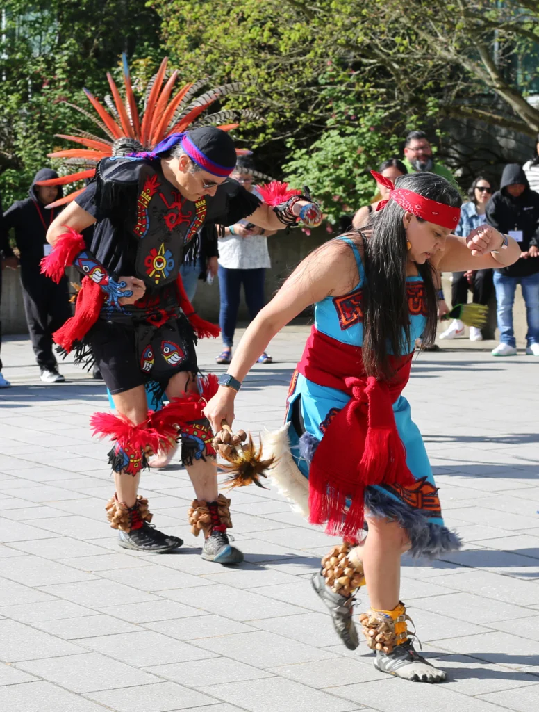 dancers in traditional garb perform in front of students