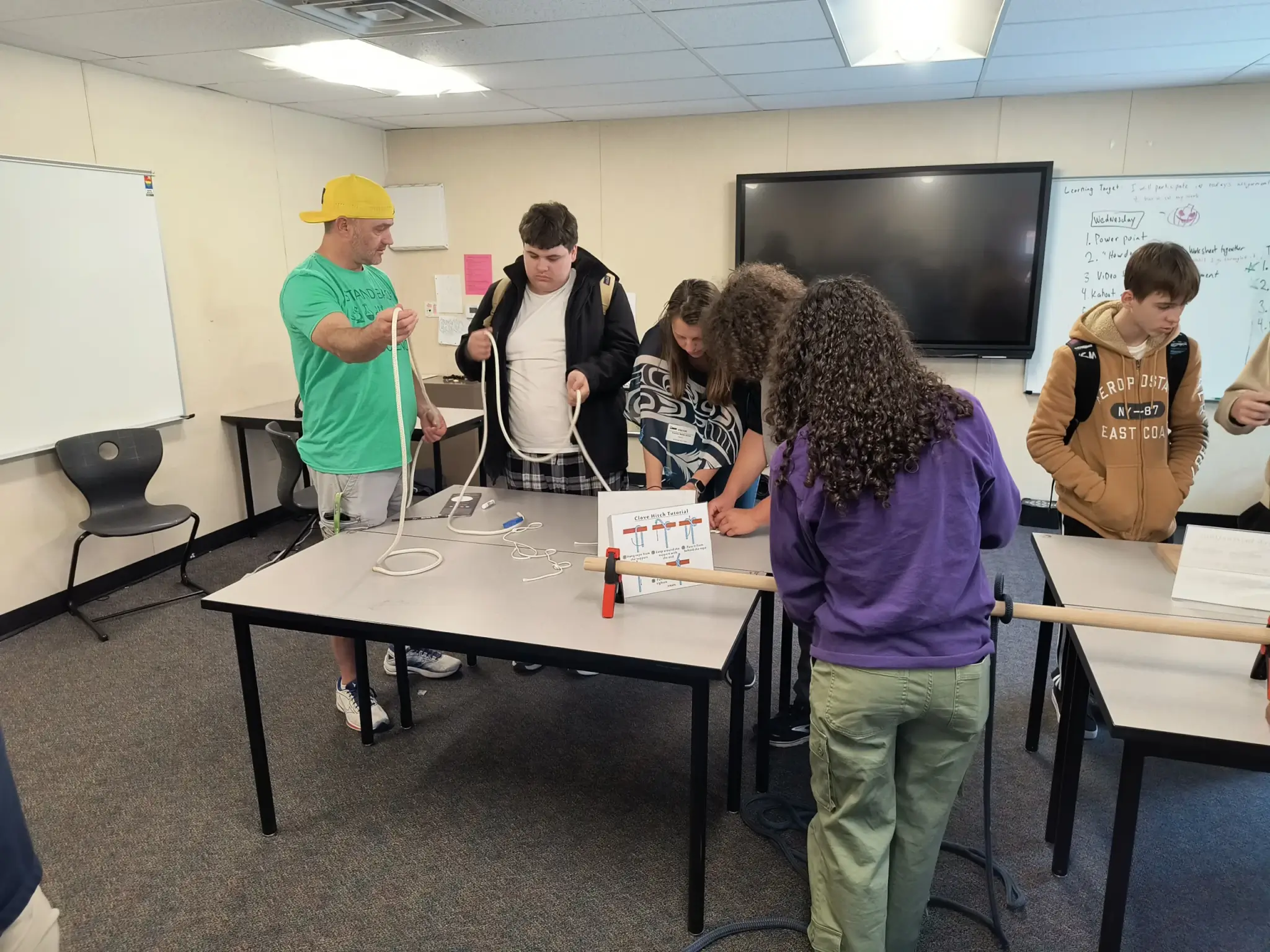 Students work at tying a knot in a length of rope.