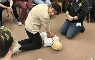 NWAmbulance_17 A student performs CPR on a mannequin while a group watches.