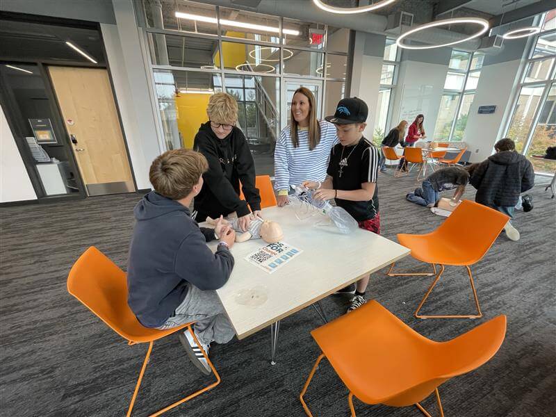 A group of student use a doll to learn CPR