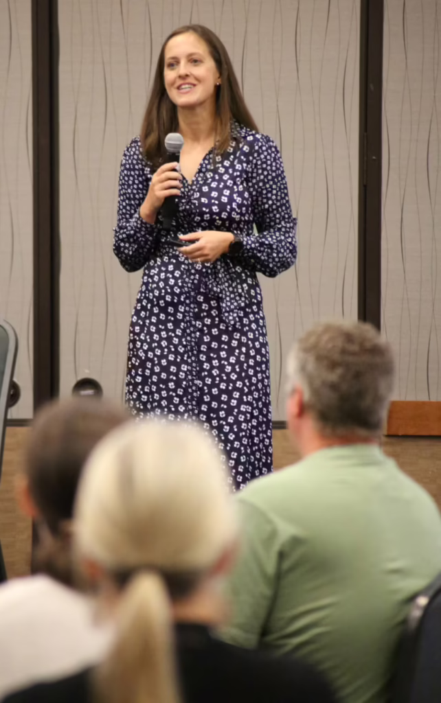 A woman holds a microphone and addresses a crowd