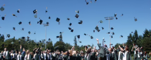 students in cap and gown outside throwing hats in the air